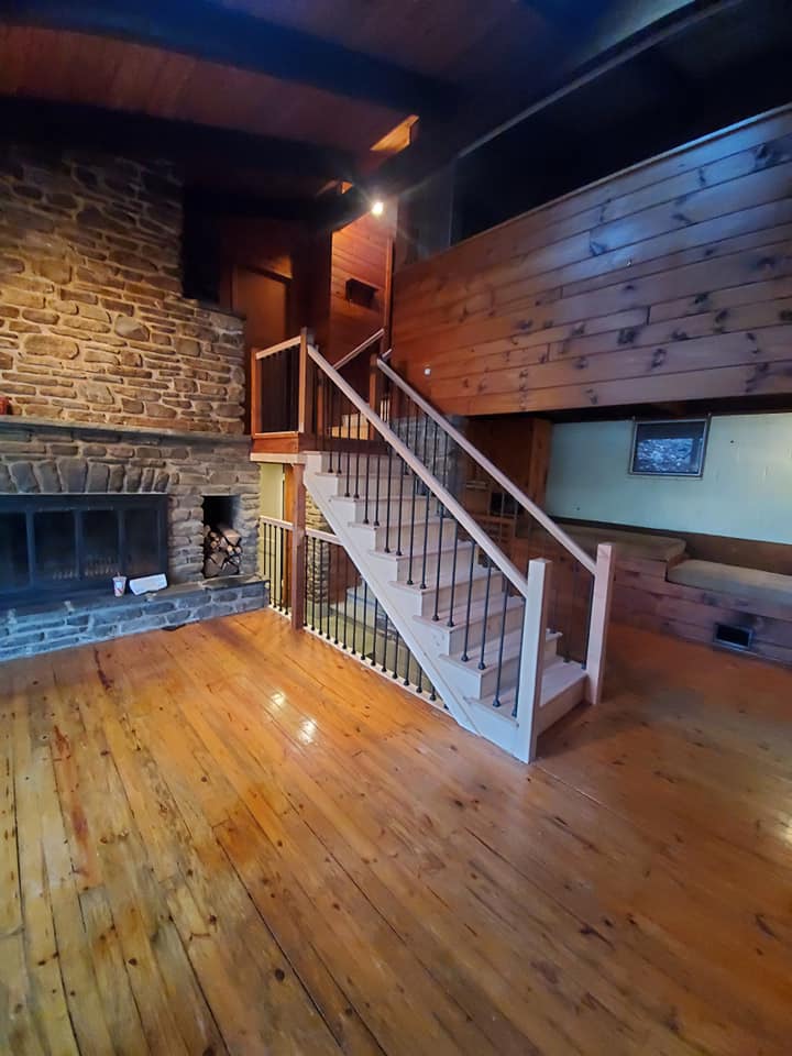 Finished staircase with iron balusters and stone fireplace