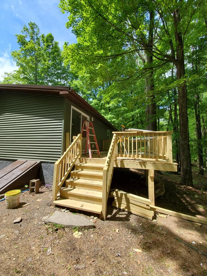 New wood deck with stairs in wooded setting